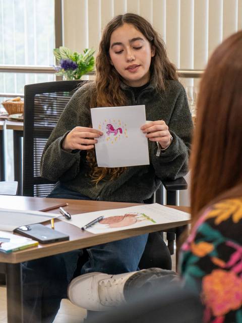 Una chica mostrando un dibujo en una reunión creativa.