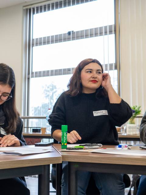 Un grupo de jóvenes trabajando en una actividad creativa en un salón de clases.
