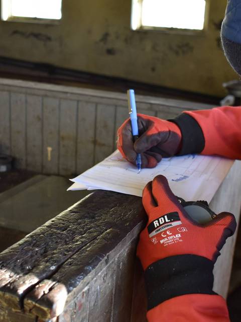Una persona está escribiendo en un papel en un ambiente rústico.