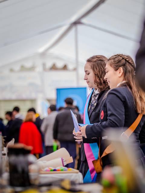 Dos jóvenes conversando en una feria de educación.
