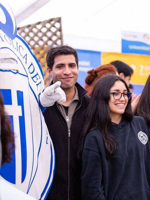Un grupo de estudiantes posando felices junto a un letrero en una actividad universitaria.