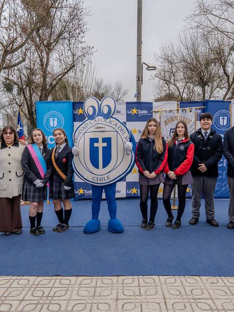 Un grupo de estudiantes y adultos posan juntos en un evento escolar al aire libre.