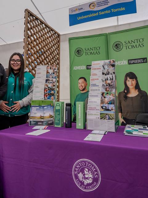 Dos estudiantes de la Universidad Santo Tomás posan en un stand durante una feria educativa.