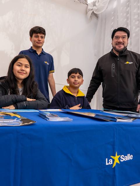 Cuatro personas posando en un stand de La Salle con una mesa y folletos.