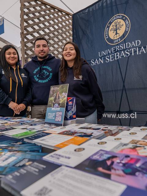 Un grupo de estudiantes muestra información sobre la Universidad San Sebastián en una feria.