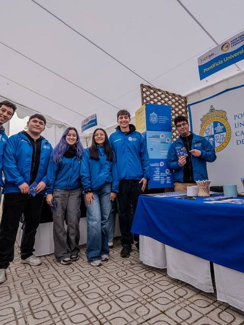 Un grupo de estudiantes de la Pontificia Universidad Católica de Chile posando en un evento con ropa azul.