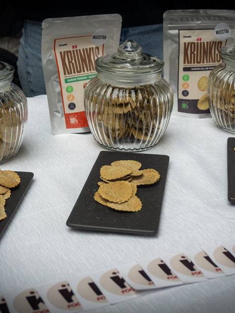 En la imagen se ven galletas crujientes exhibidas en frascos de vidrio y platos negros.