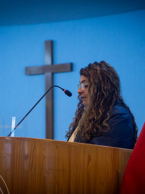 Una mujer habla en un evento religioso en una iglesia chilena.