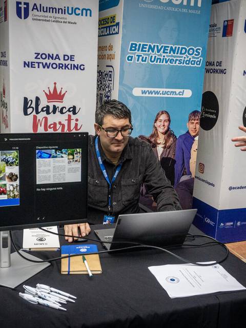 Un hombre está atendiendo a un visitante en un stand de networking de una universidad.