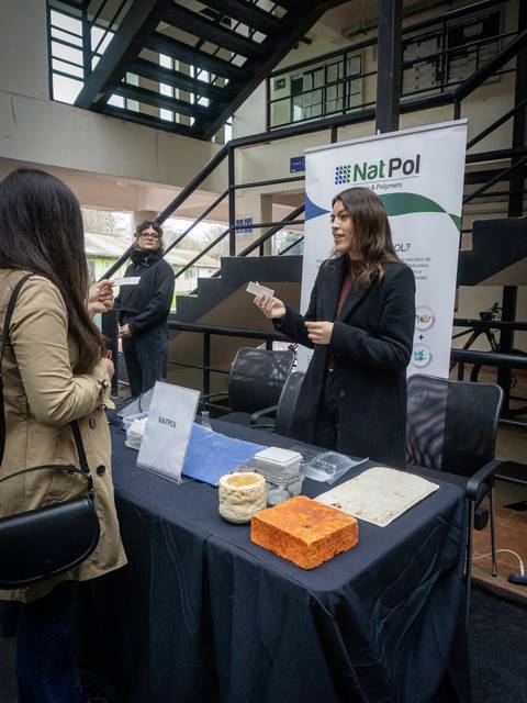 Una mujer en un stand muestra productos a una asistente en un evento.