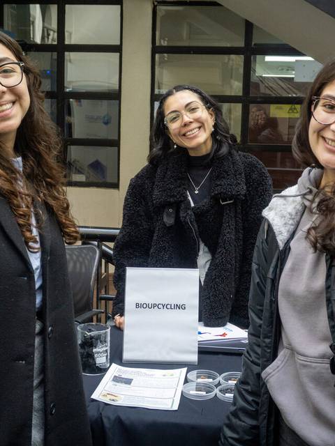 Tres chicas sonrientes posando en un evento sobre biociclaje.