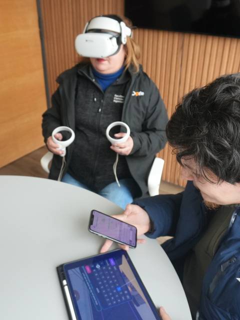 Dos personas interactuando con tecnología de realidad virtual en un ambiente moderno.
