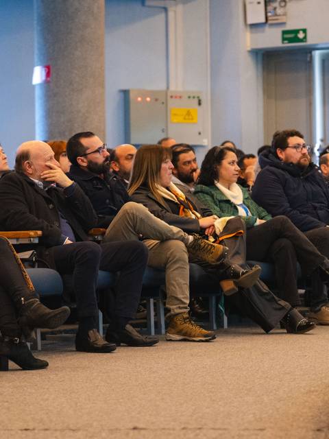 Un grupo de personas sentadas en un auditorio, prestando atención a un evento.