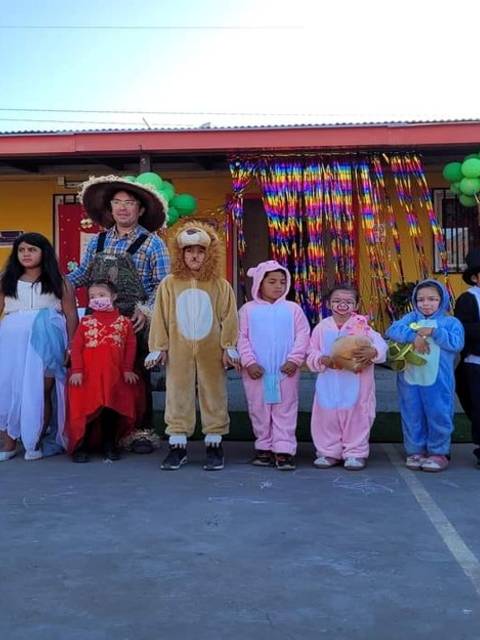 Un grupo de niños y adultos vestidos con trajes de personajes en una celebración en una escuela.