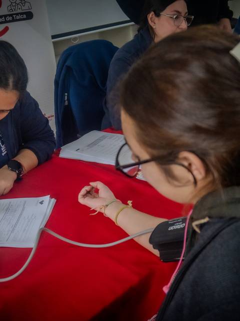 Una mujer toma la presión arterial a otra persona en una actividad de salud.