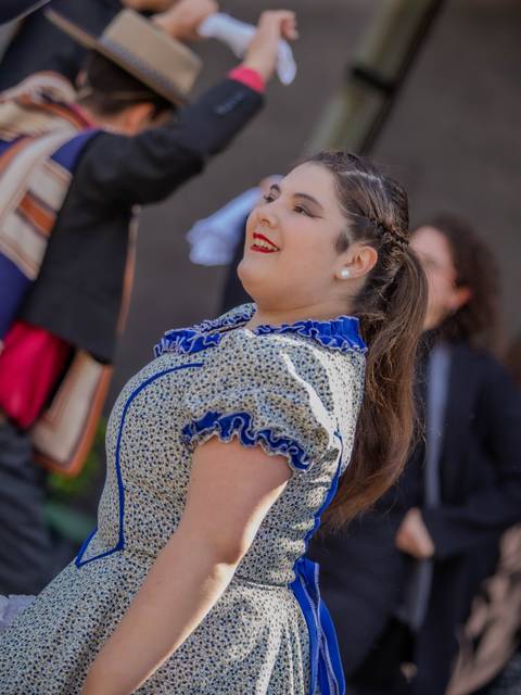 Una joven bailando feliz con un vestido tradicional chileno en una celebración.