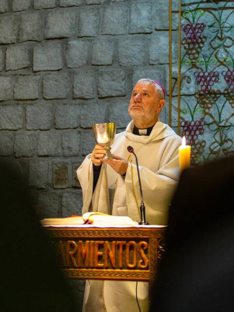 Un sacerdote realiza un rito religioso sosteniendo un cáliz en una ceremonia.