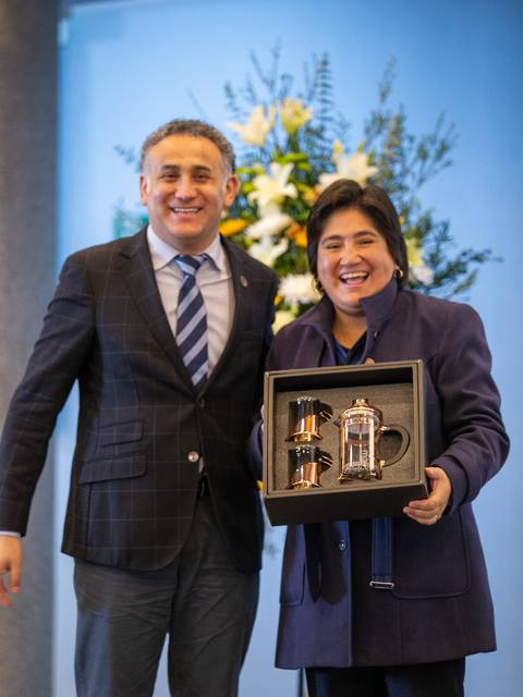 Unos profesionales sonrientes posando con un regalo en una ceremonia.