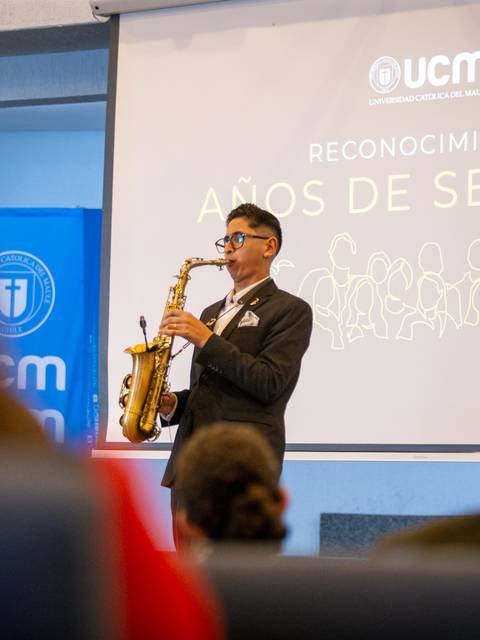 Un joven tocando saxofón en un evento de reconocimiento en la UCM.