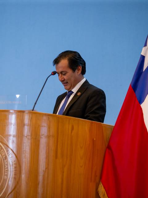 Un hombre en un podio lee un discurso en un evento formal en Chile.