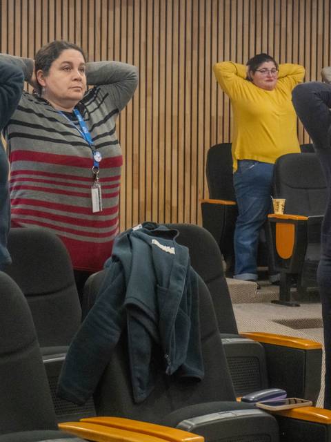 Un grupo de mujeres se encuentra realizando ejercicios de estiramiento en una sala de reuniones.