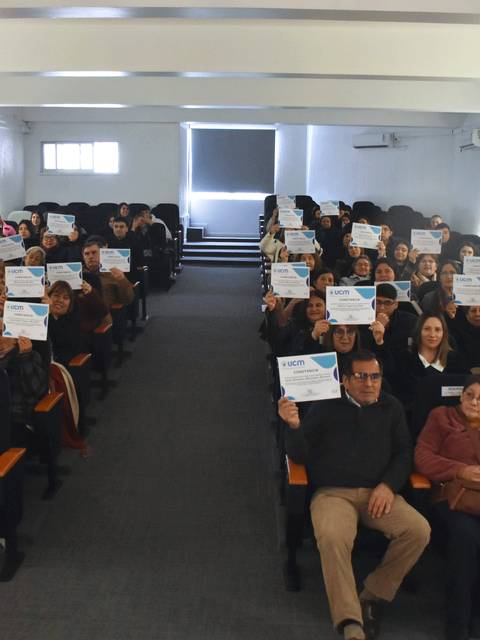 Un grupo de personas en un auditorio sosteniendo carteles.