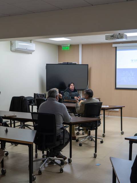 Una charla educativa en un aula de universidad con varios asistentes atentos.
