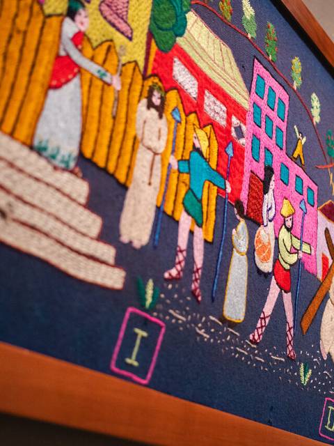 Una obra de arte textil colorida que representa escenas de la vida cotidiana en un pueblo chileno.