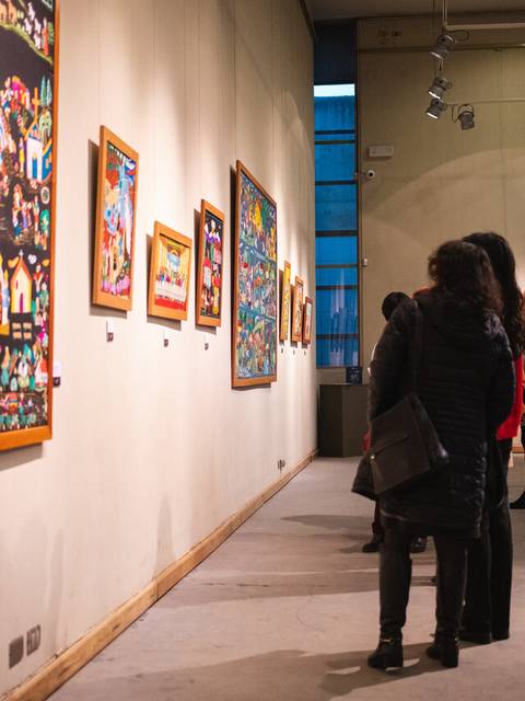 Una exposición de arte donde la gente admira coloridas obras en las paredes.