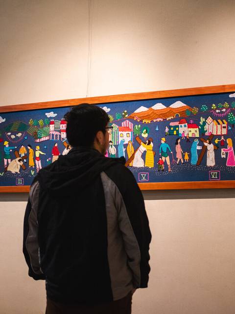 Una persona observa una colorida obra de arte en una galería.