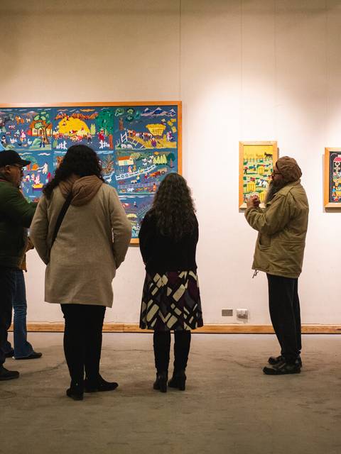 Un grupo de personas observa obras de arte en una galería.