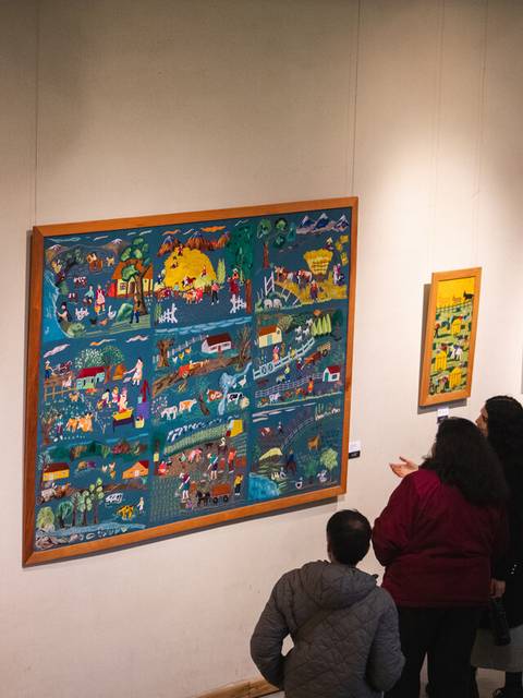 Un grupo de personas observa pinturas coloridas en una galería de arte en Chile.