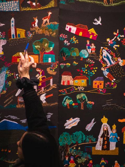 Una pareja observa un colorido mural que representa escenas de la vida campesina chilena.