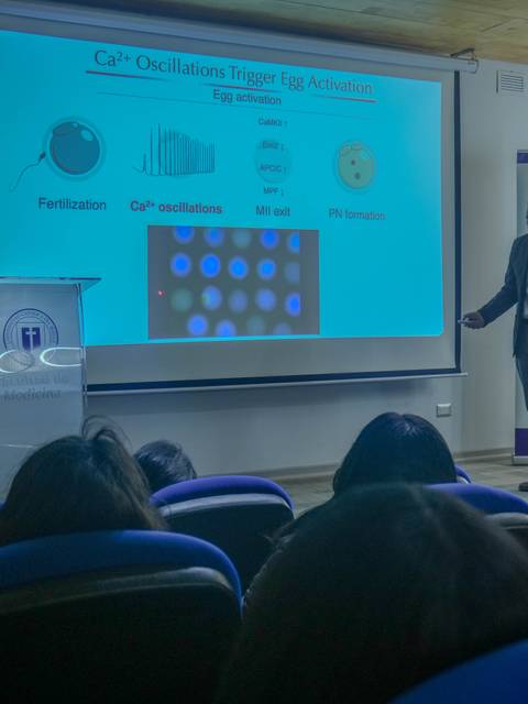 Un charlista presenta un tema científico sobre oscilaciones de calcio en un auditorio.