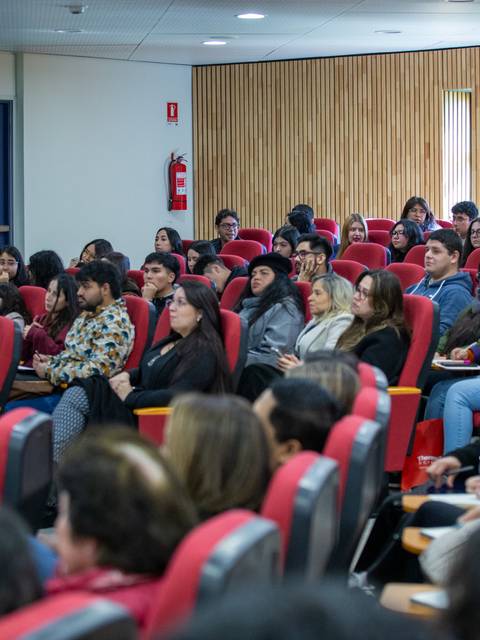 Una multitud de personas sentadas en un auditorio, escuchando atentamente.