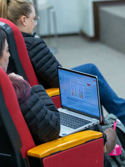 Un grupo de personas en asientos de auditorium trabajando en laptops.