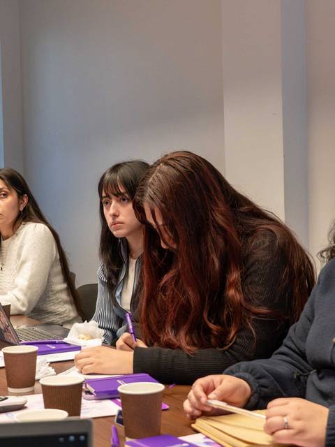 Un grupo de mujeres está participando activamente en una reunión en una sala de conferencias.