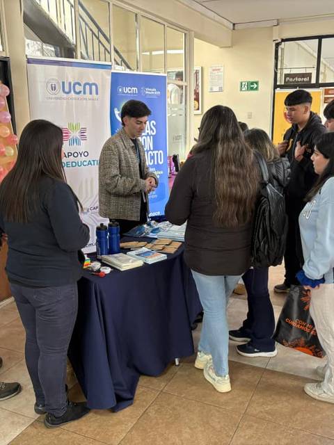 Un grupo de estudiantes se reúne en un stand informativo de la UCM.