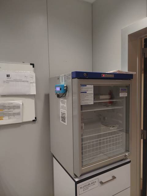 Un refrigerador médico ubicado en una habitación con paredes claras.