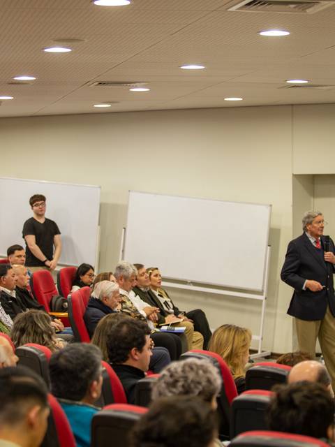 Un evento con muchas personas sentadas escuchando a un orador en un auditorio.