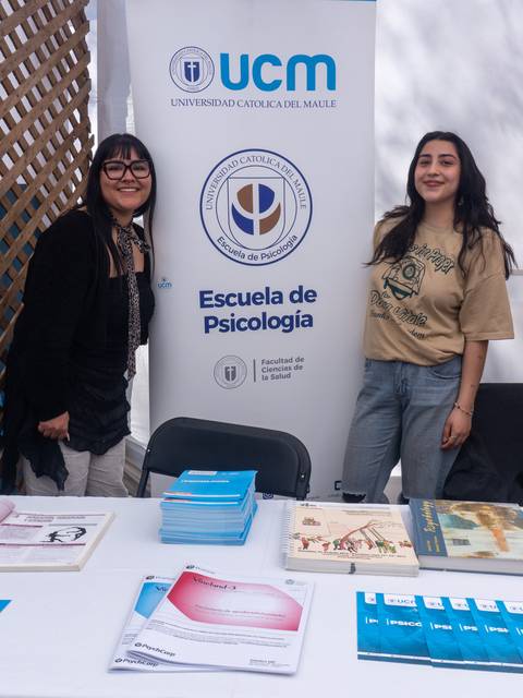 Dos chicas sonriendo en un stand de la Universidad Católica del Maule.