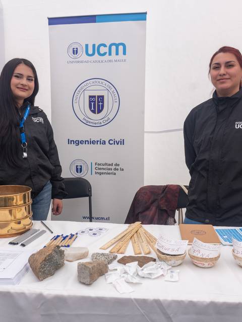 Dos estudiantes de ingeniería civil muestran su stand en una feria universitaria.