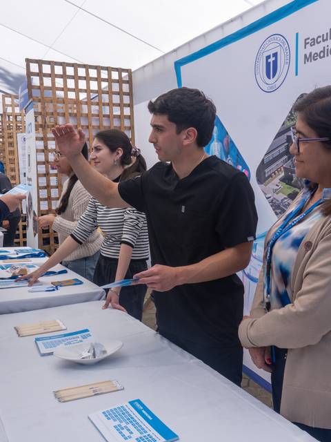 Un grupo de personas interactuando en un stand de la Facultad de Medicina en una feria.