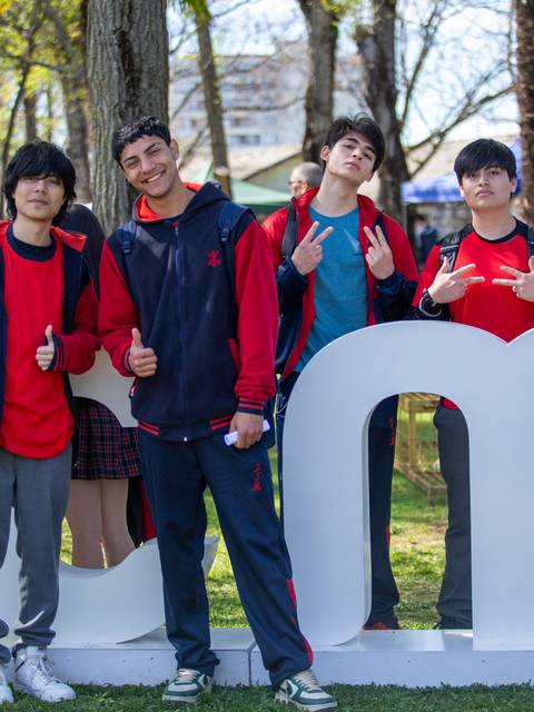 Un grupo de estudiantes posando felices frente a un letrero de la universidad.