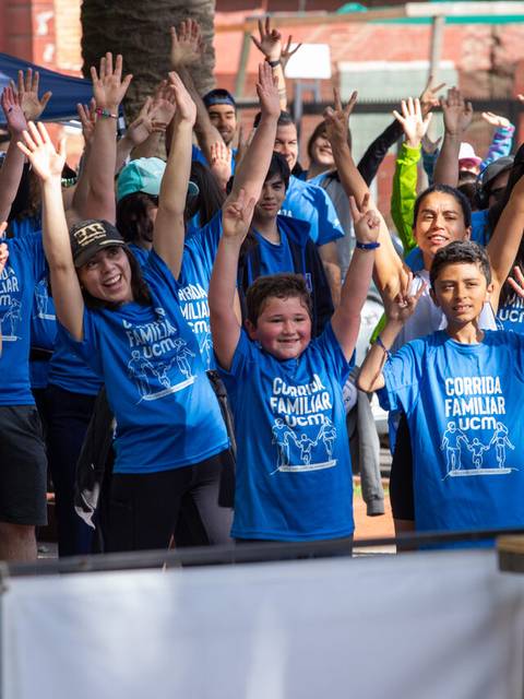 Un grupo de niños y adultos con poleras azules celebrando en un evento familiar.