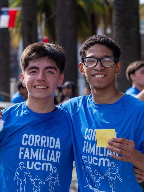 Dos amigos sonrientes participan en una corrida familiar en la playa.
