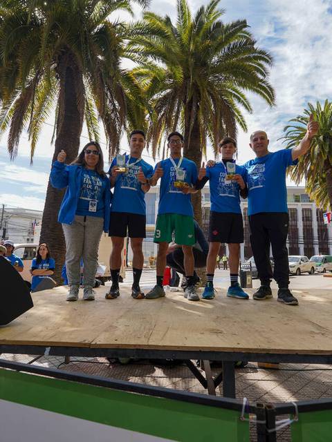 Un grupo de personas celebra en un podio tras una competencia deportiva en un día soleado.