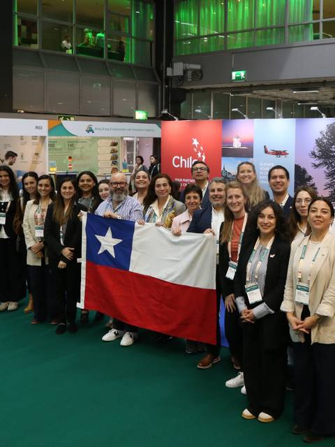 Grupo de mujeres chilenas levantando la bandera de Chile en un evento.