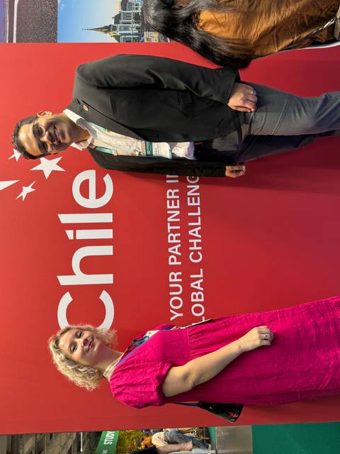 Personas posando frente a un cartel que dice 'Chile'.