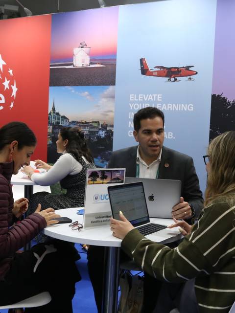 En la imagen se observa un stand de Chile en una feria, donde varias personas interactúan sentadas alrededor de una mesa.